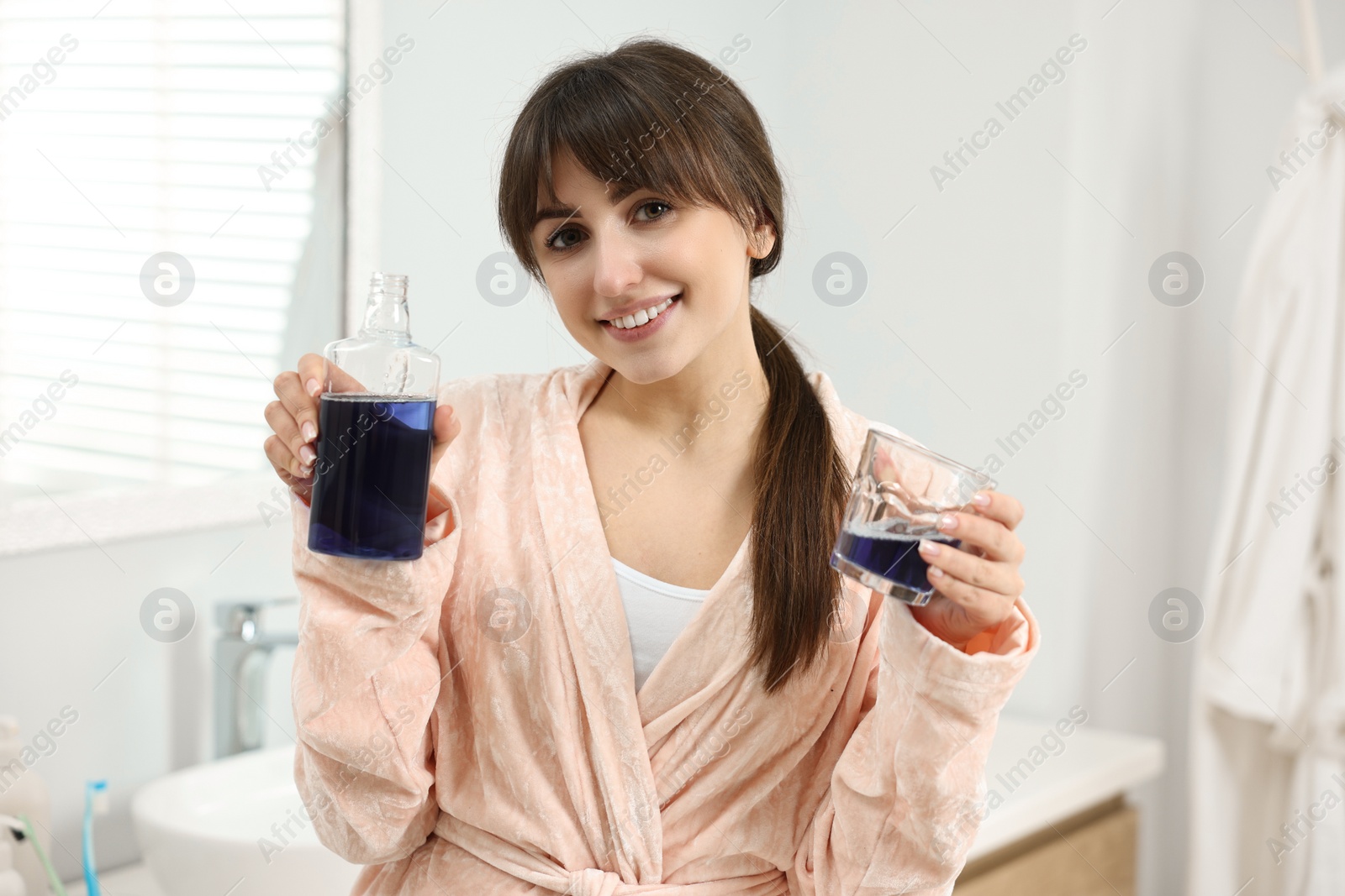 Photo of Young woman with mouthwash in bathroom. Oral hygiene