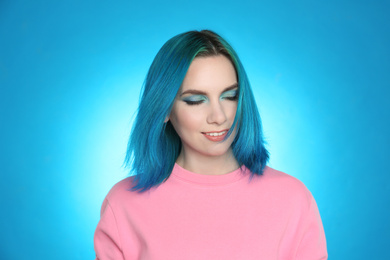 Young woman with bright dyed hair on light blue background