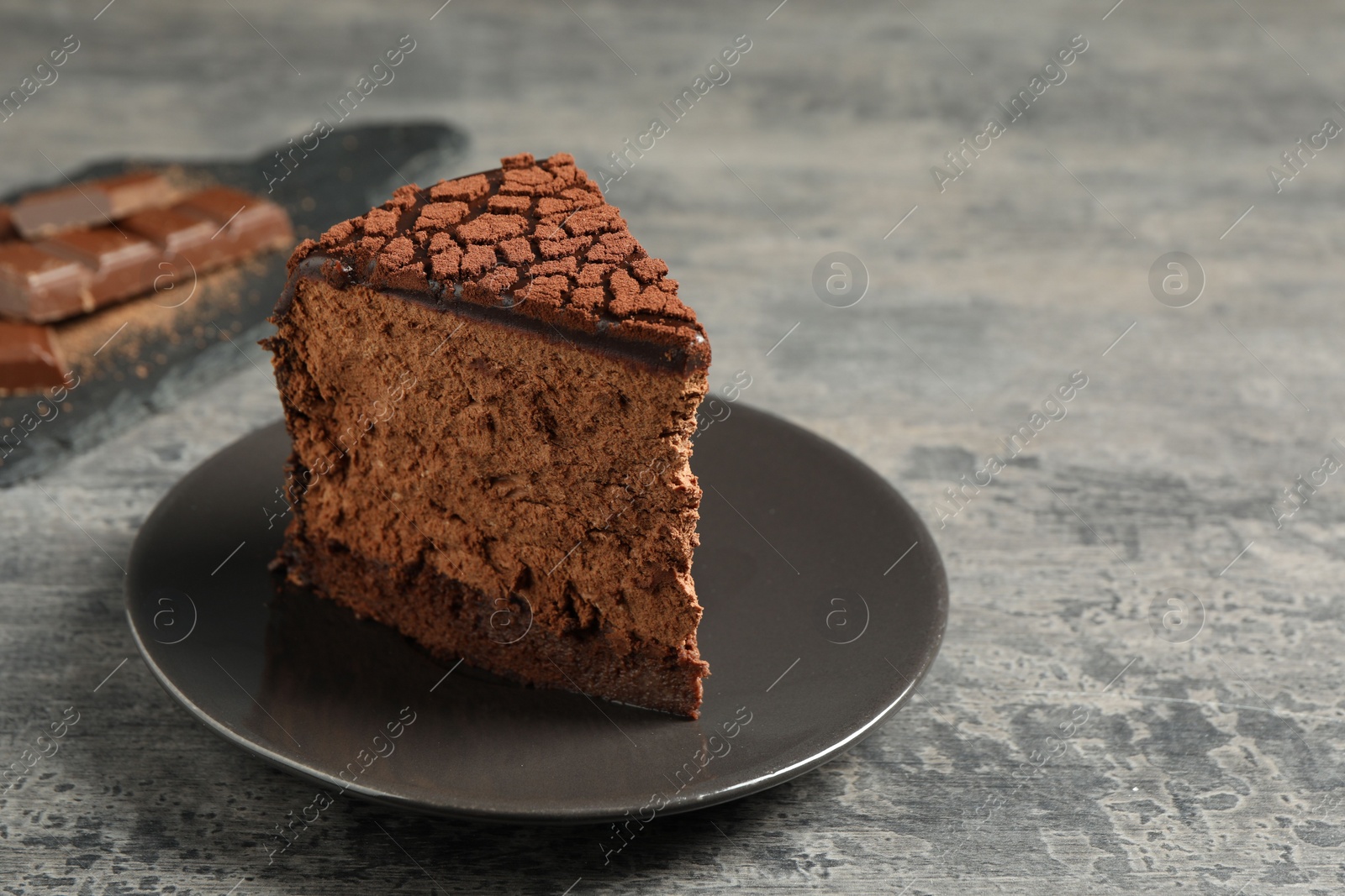 Photo of Piece of delicious chocolate truffle cake on grey textured table, closeup