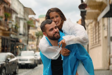 Photo of Young couple in raincoats enjoying time together on city street