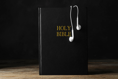 Bible and earphones on wooden table. Religious audiobook