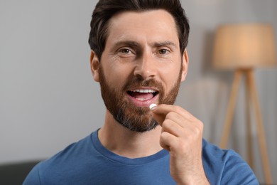 Photo of Portrait of handsome man taking pill indoors