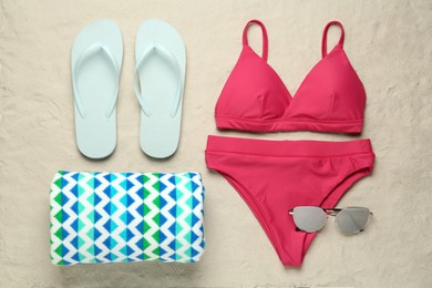 Photo of Stylish bikini and beach accessories on sand, flat lay