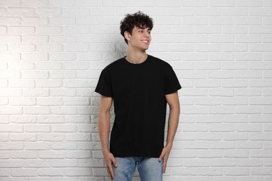 Man wearing black t-shirt near white brick wall. Mockup for design