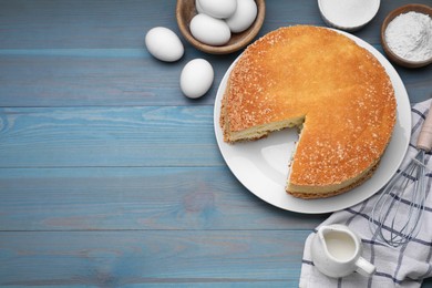 Tasty sponge cake, whisk and ingredients on light blue wooden table, flat lay. Space for text