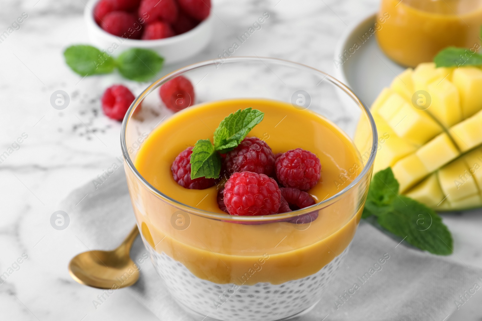 Photo of Delicious chia pudding with mango sauce and raspberries on table, closeup