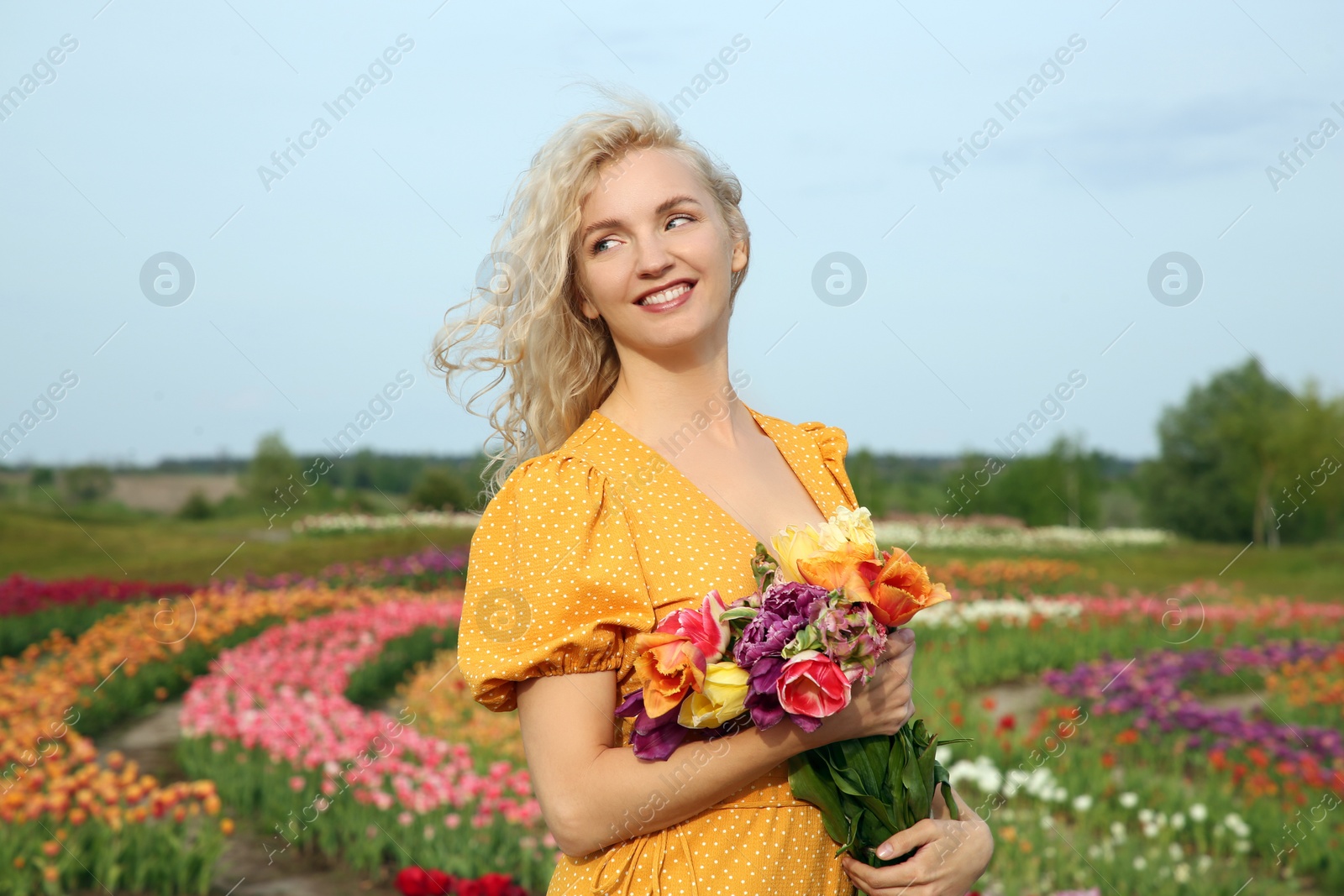 Photo of Happy woman with spring bouquet of flowers in beautiful tulip field