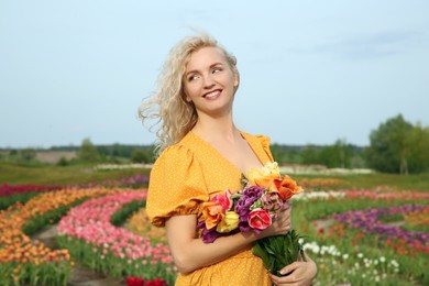 Happy woman with spring bouquet of flowers in beautiful tulip field