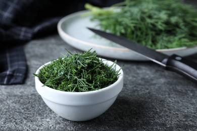 Photo of Bowl of fresh dill on grey table, space for text