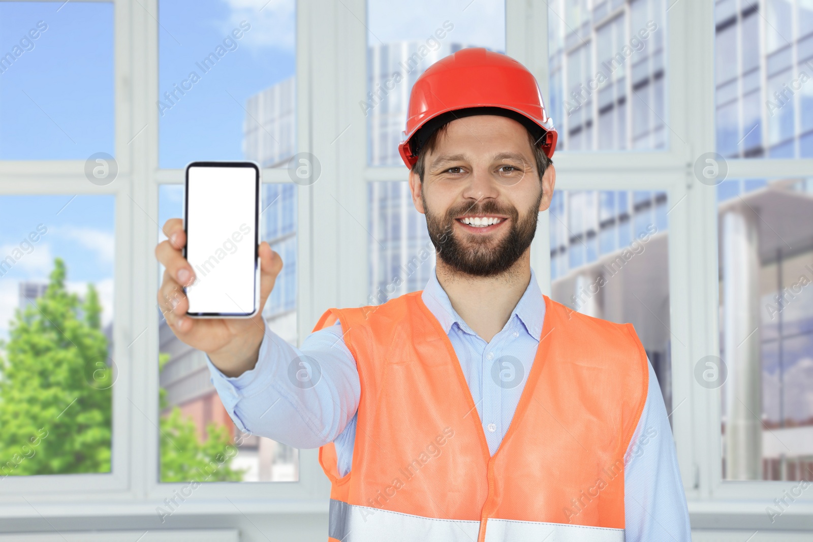 Photo of Man in reflective uniform with phone indoors