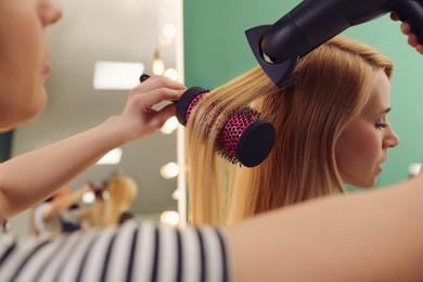 Photo of Stylist blow drying woman's hair in salon