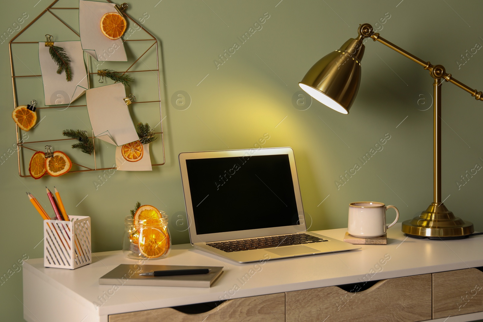 Photo of Stylish workplace with handmade decor made of dry orange slices and notes