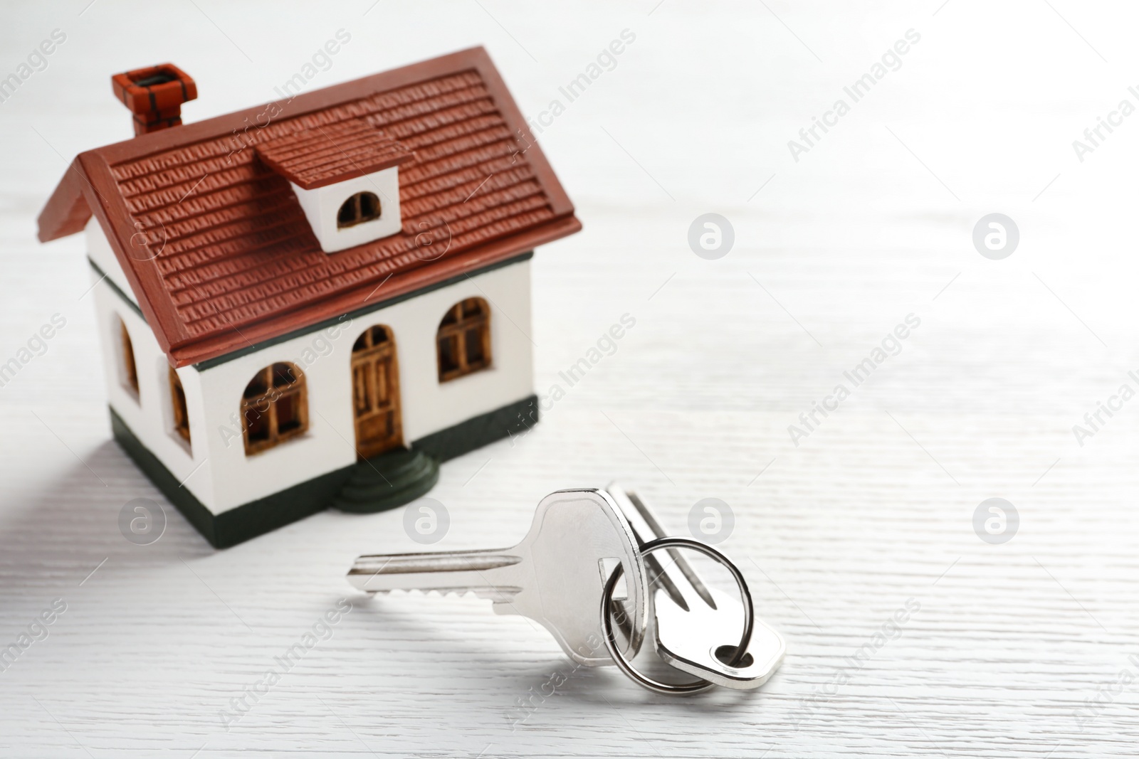 Photo of Keys and house model on wooden table. Real estate agent services