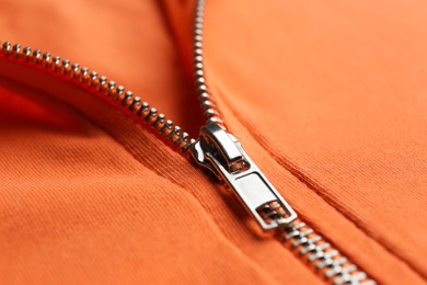 Photo of Orange sweatshirt with zipper as background, closeup view