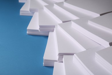 Many stacks of paper sheets on blue background, closeup