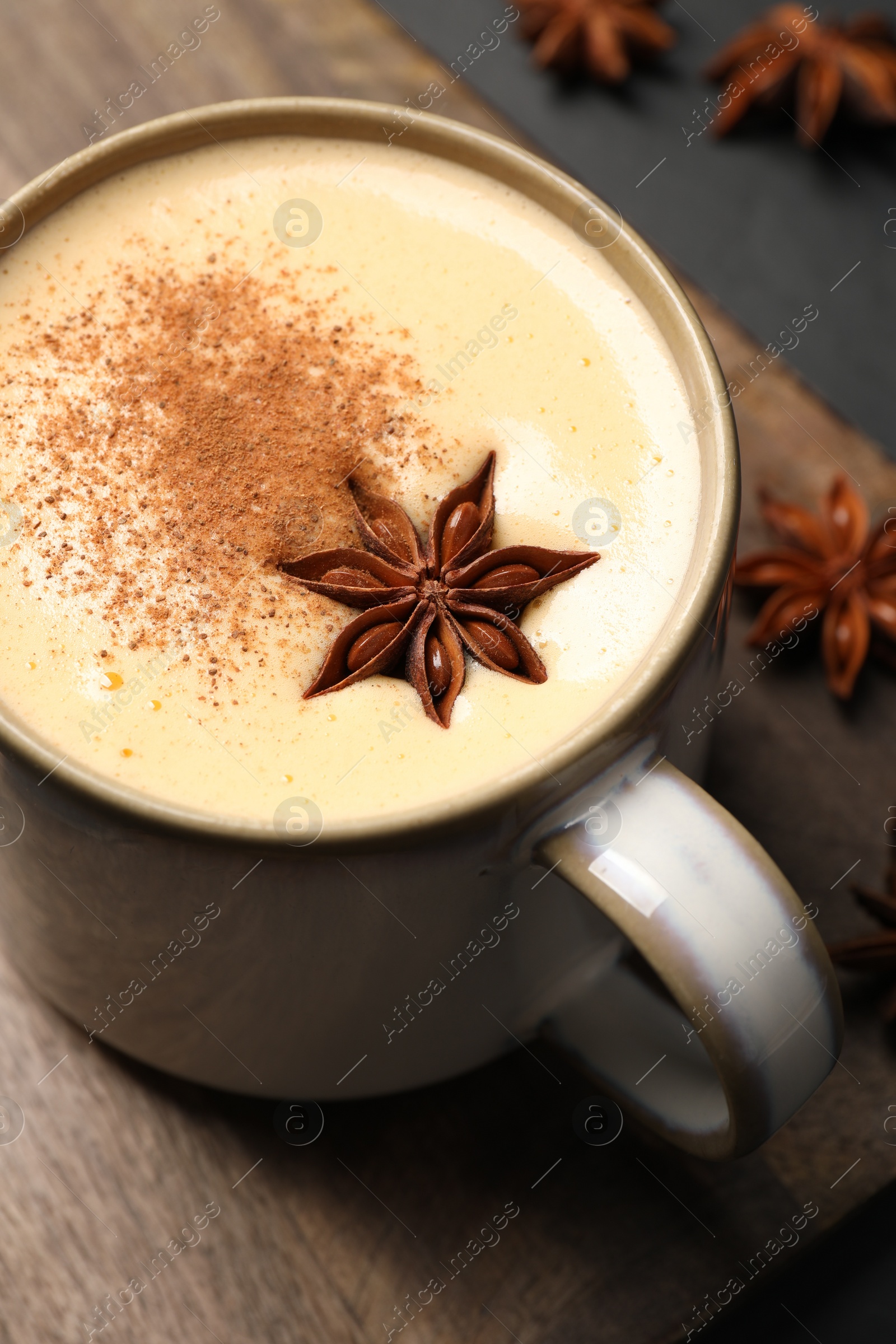 Photo of Delicious eggnog with anise and cinnamon on black table, above view