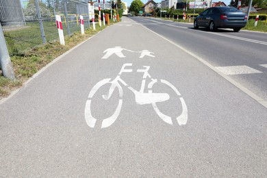 Bicycle lane with white sign painted on asphalt near road