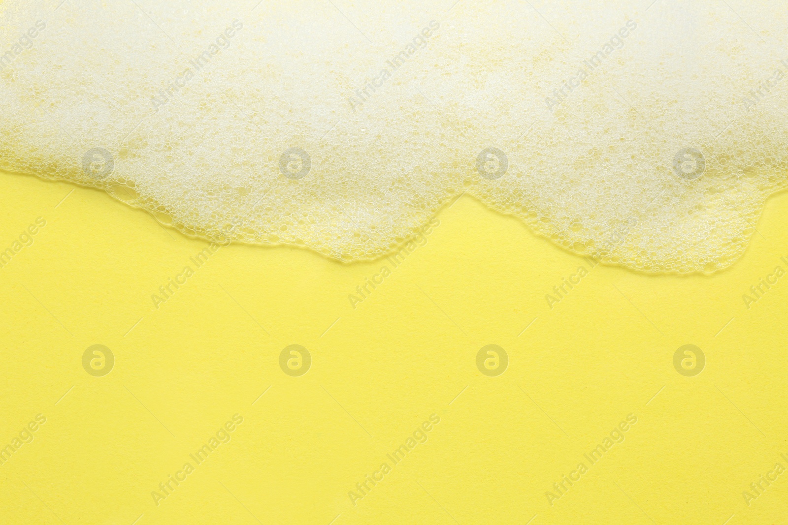 Photo of Fluffy bath foam on yellow background, top view. Space for text