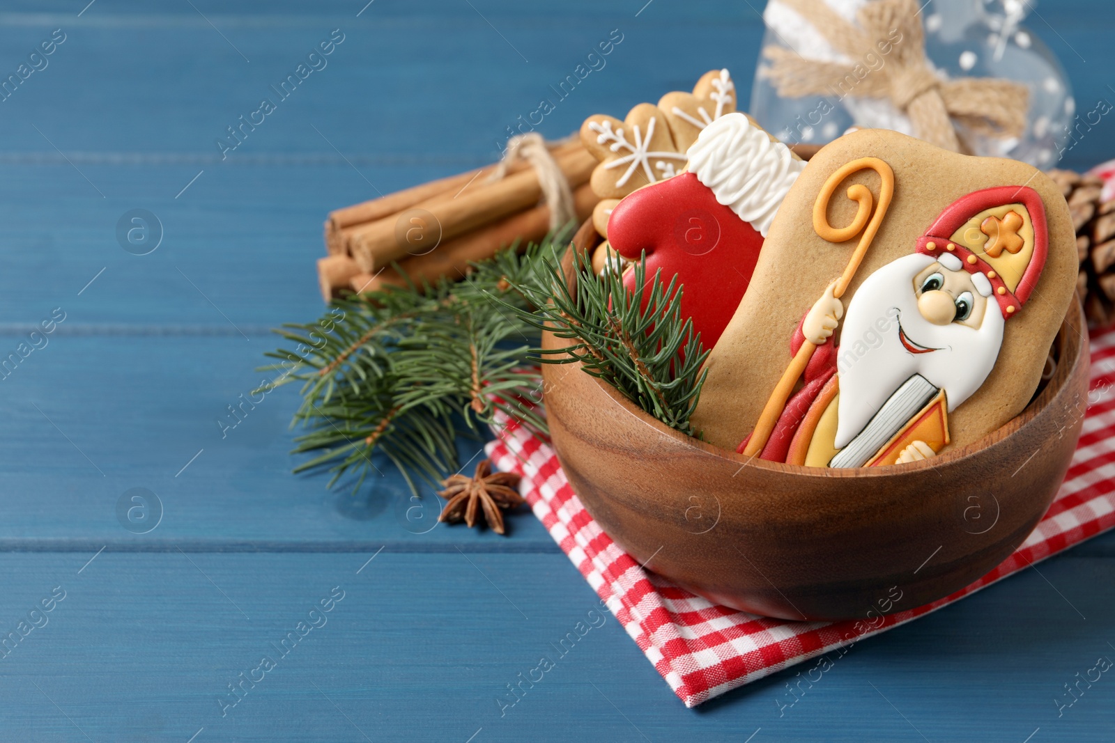 Photo of Tasty gingerbread cookies and fir branches on blue wooden table, space for text. St. Nicholas Day celebration