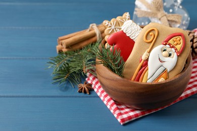 Tasty gingerbread cookies and fir branches on blue wooden table, space for text. St. Nicholas Day celebration