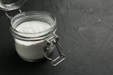 Baking powder in jar on black textured table, space for text