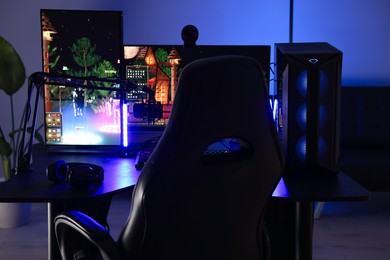 Photo of Playing video games. Stylish room interior with modern computer and gaming chair in neon lights