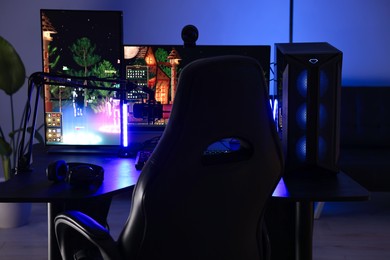 Playing video games. Stylish room interior with modern computer and gaming chair in neon lights