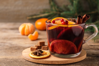 Photo of Glass cup with tasty mulled wine on wooden table