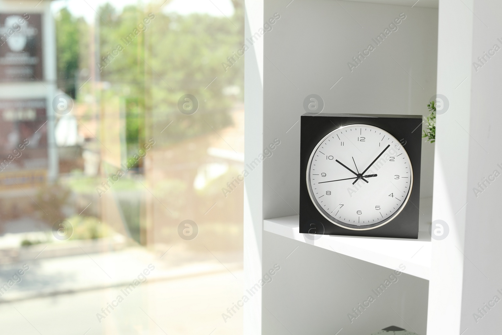 Photo of Analog clock on shelf indoors. Time of day