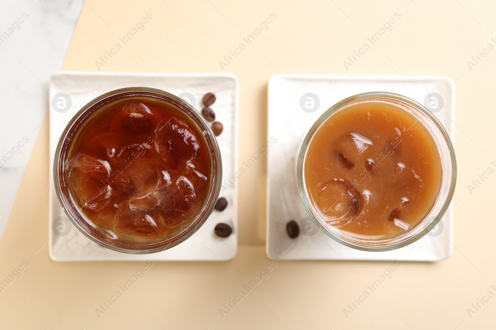 Photo of Refreshing iced coffee with milk in glasses on beige table, flat lay