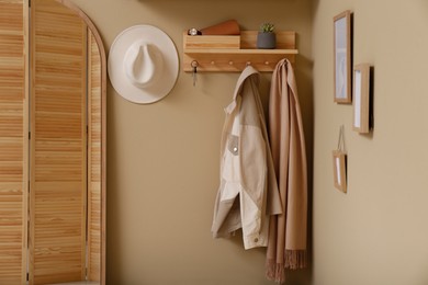 Photo of Hallway interior with stylish accessories and wooden hanger for keys on beige wall