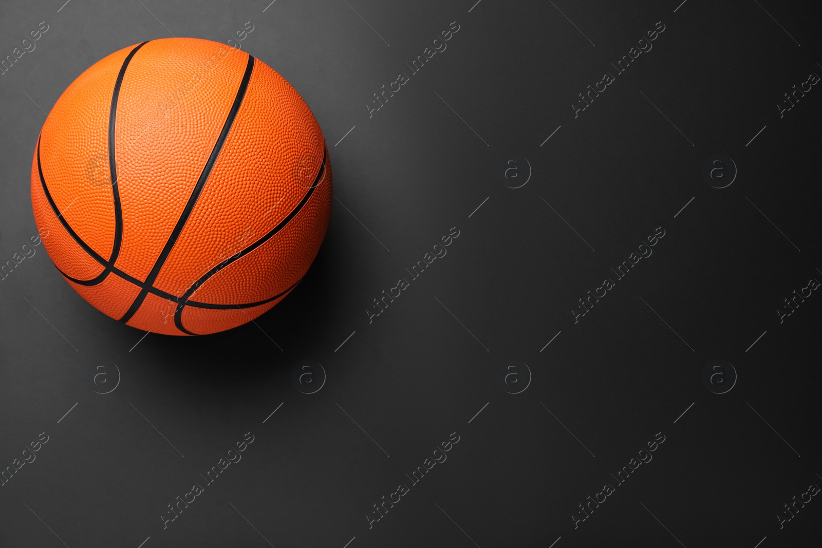 Photo of Orange ball on black background, top view with space for text. Basketball equipment