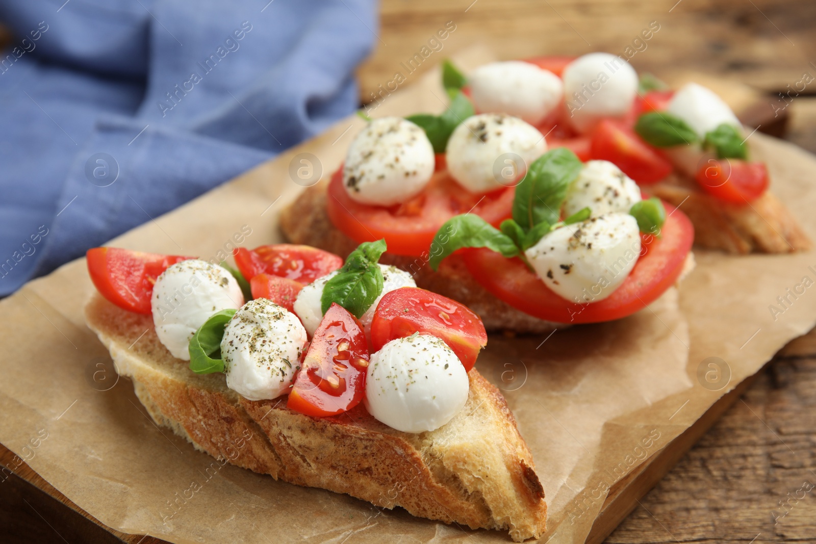 Photo of Delicious sandwiches with mozzarella, fresh tomatoes and basil on parchment