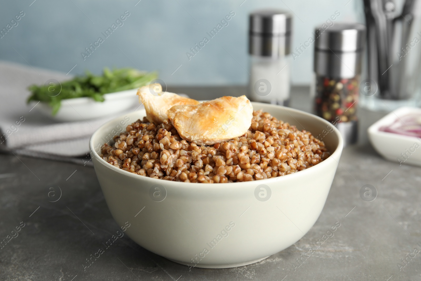 Photo of Tasty buckwheat porridge with meat on grey table