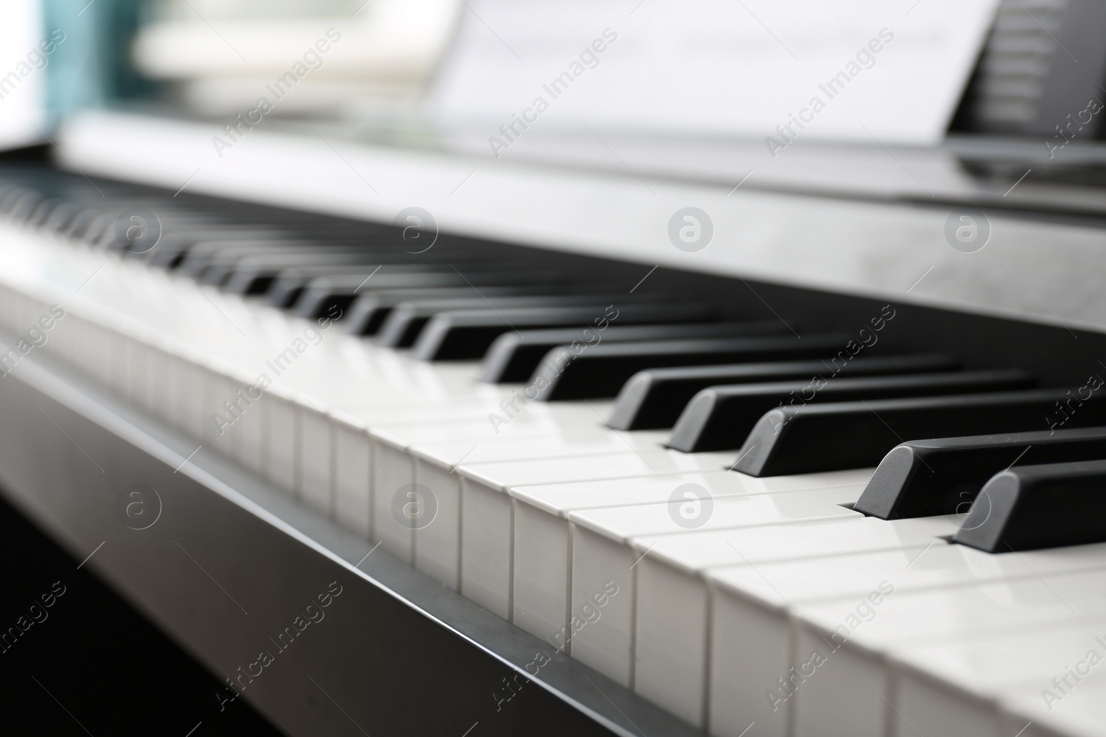 Photo of Modern piano with music sheets in room, closeup