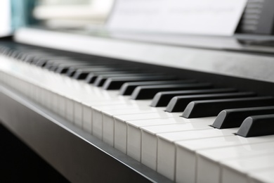 Photo of Modern piano with music sheets in room, closeup