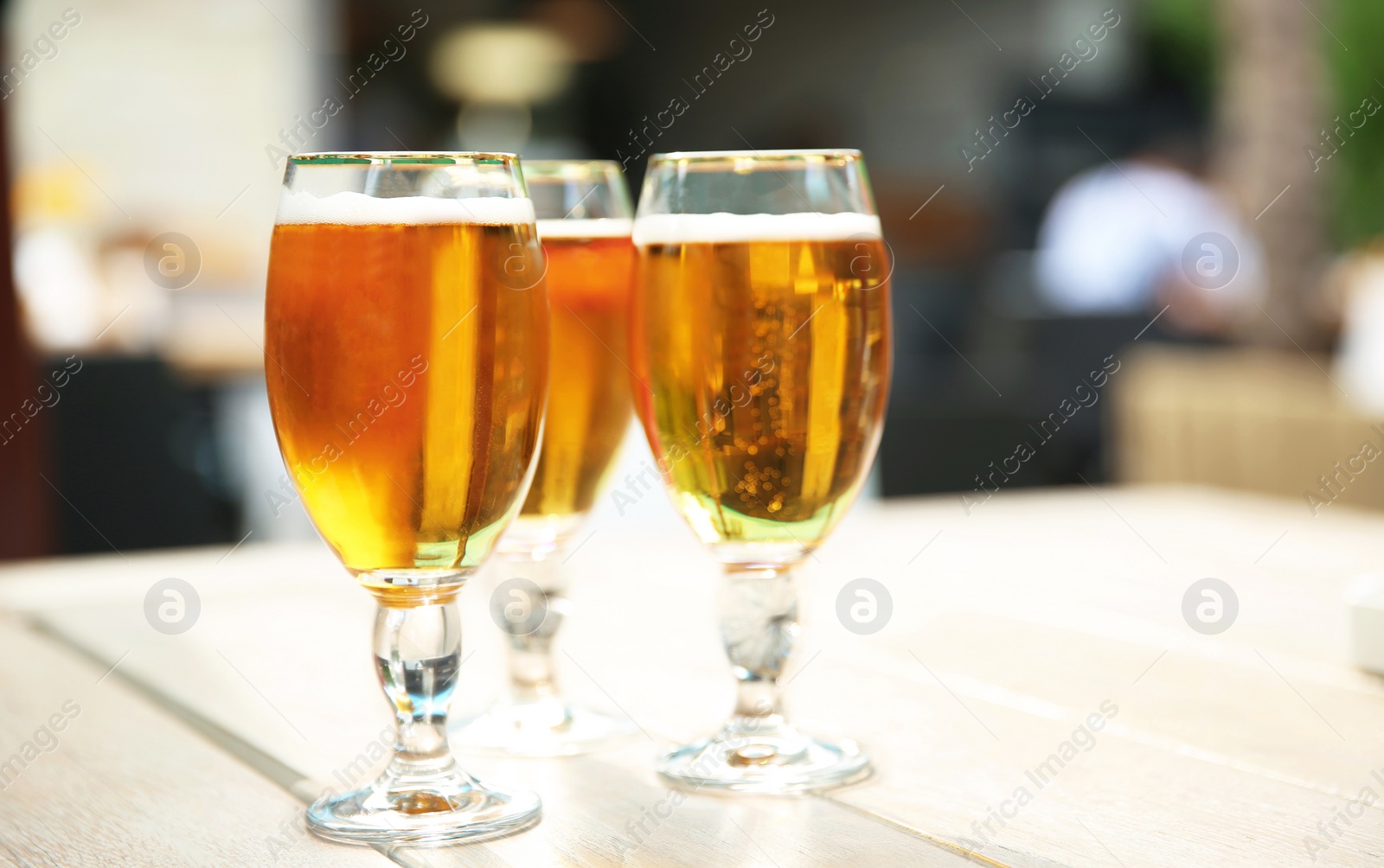 Photo of Glasses with cold beer on table against blurred background