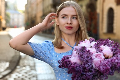 Photo of Beautiful woman with bouquet of spring flowers on city street