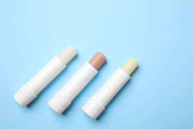 Hygienic lipsticks on light blue background, flat lay