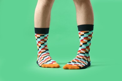 Photo of Man in stylish colorful socks on light green background, closeup