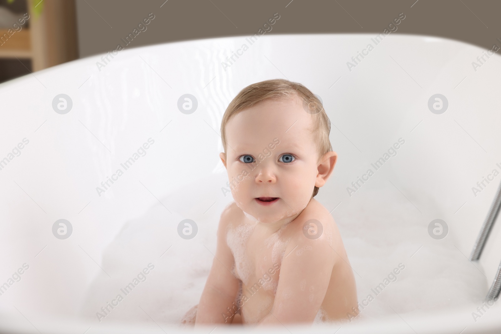 Photo of Cute little baby bathing in tub at home