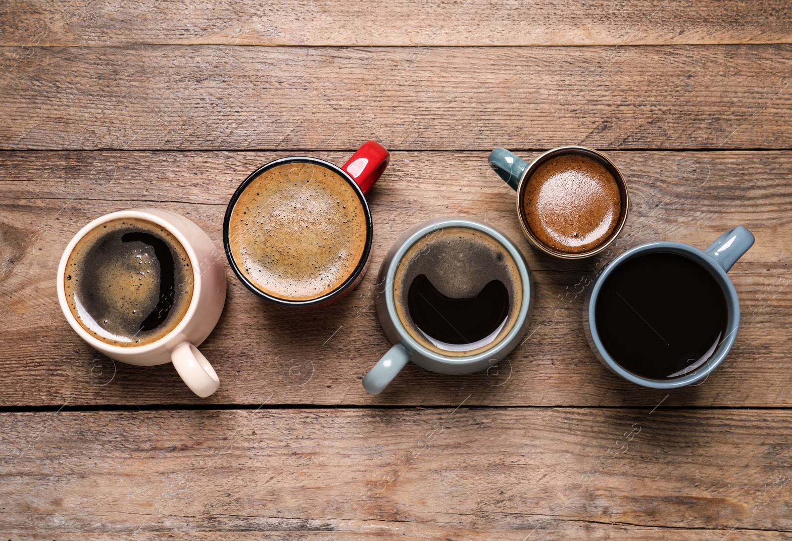 Photo of Cups of hot coffee on wooden table, flat lay