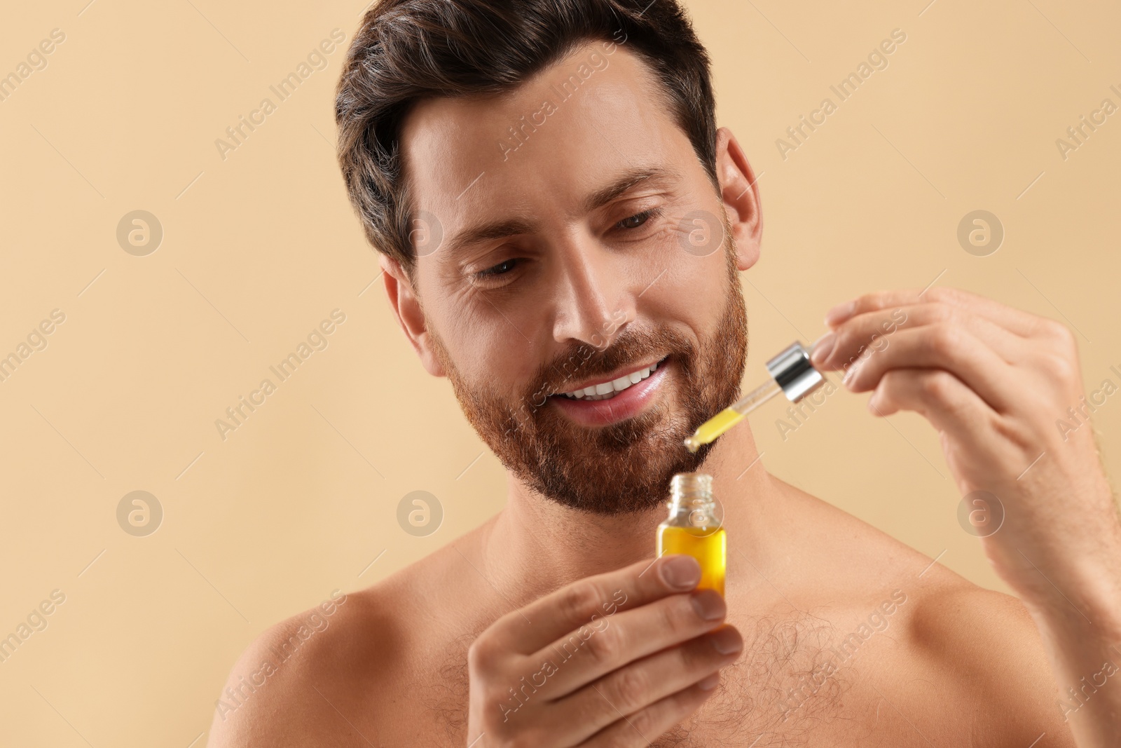 Photo of Smiling man with cosmetic serum on beige background, closeup