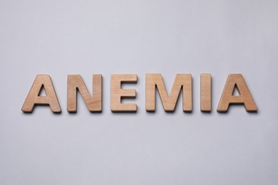 Photo of Word Anemia made of wooden letters on grey background, flat lay