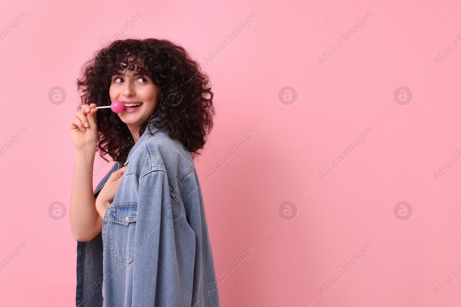 Photo of Beautiful woman with lollipop on pink background, space for text