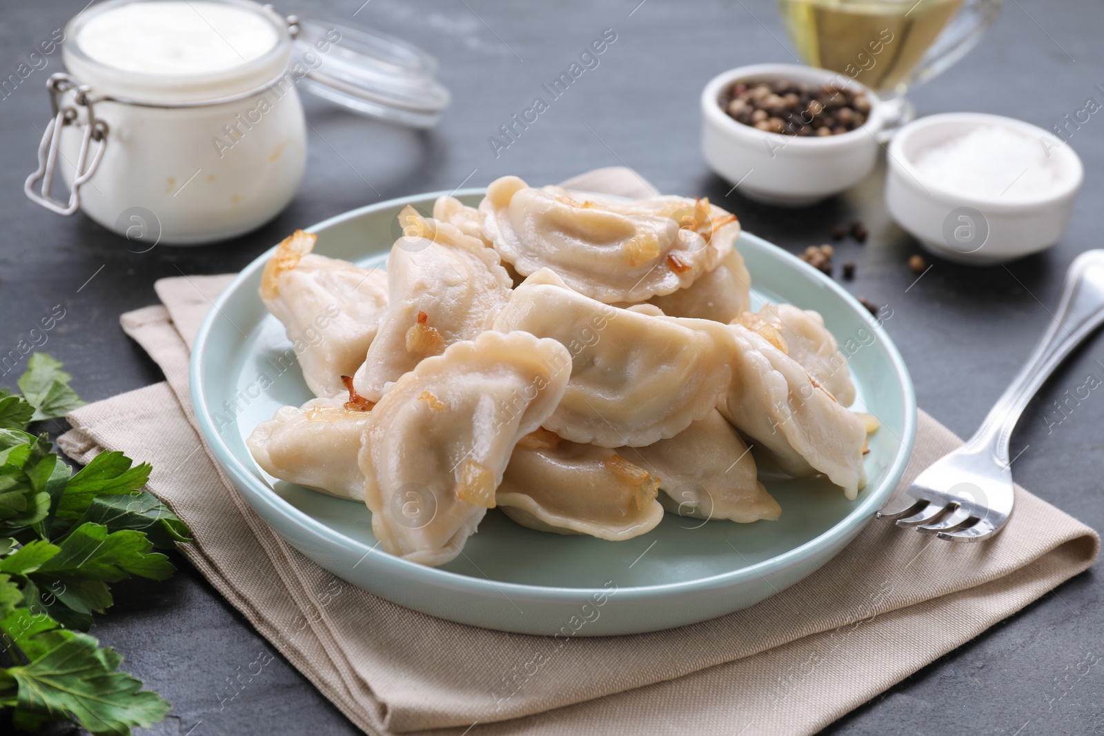 Photo of Delicious dumplings (varenyky) with potatoes and onion served on black table