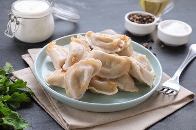 Photo of Delicious dumplings (varenyky) with potatoes and onion served on black table