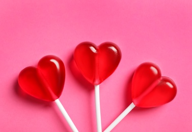 Photo of Sweet heart shaped lollipops on pink background, flat lay. Valentine's day celebration