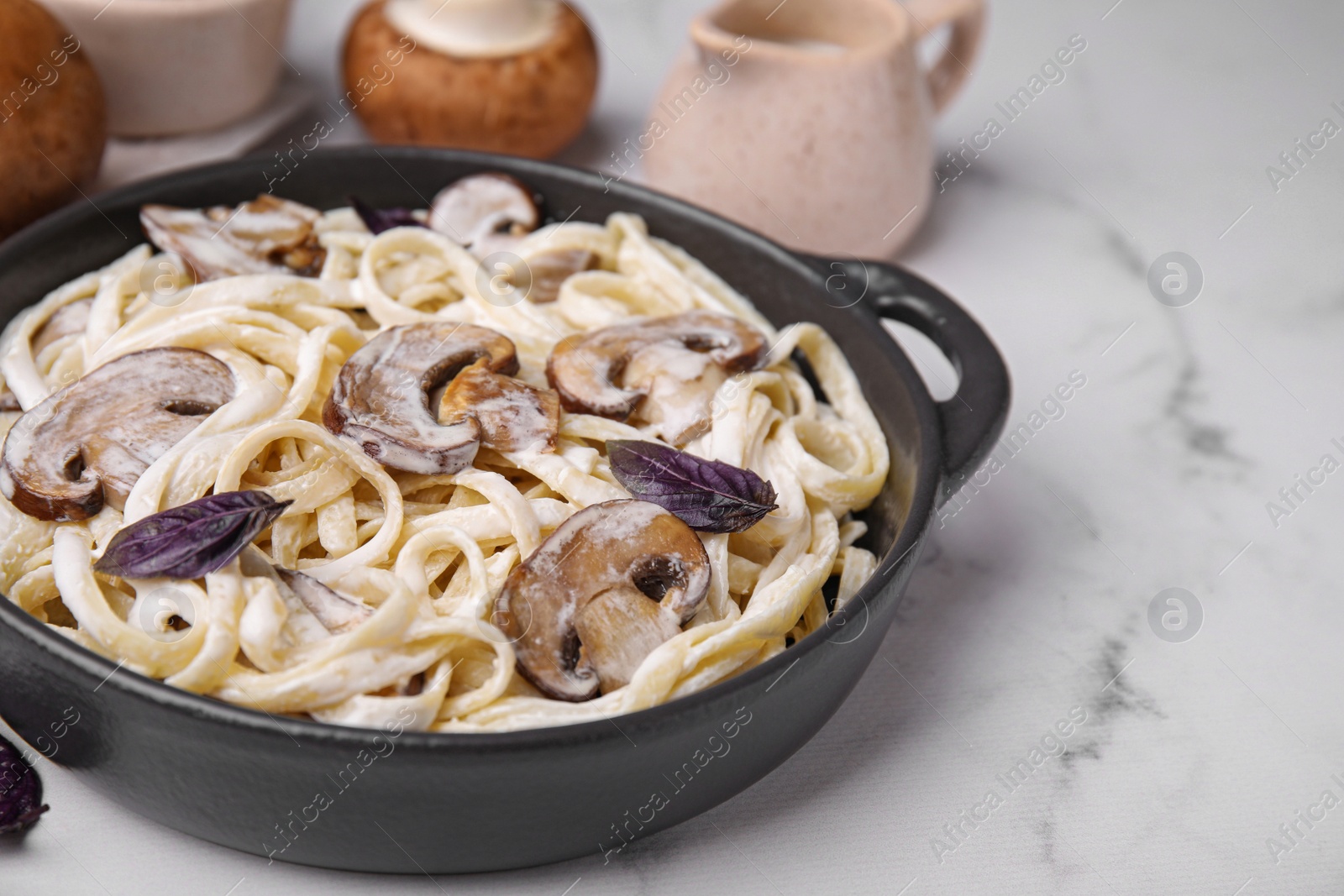 Photo of Delicious pasta with mushrooms on white marble table, closeup