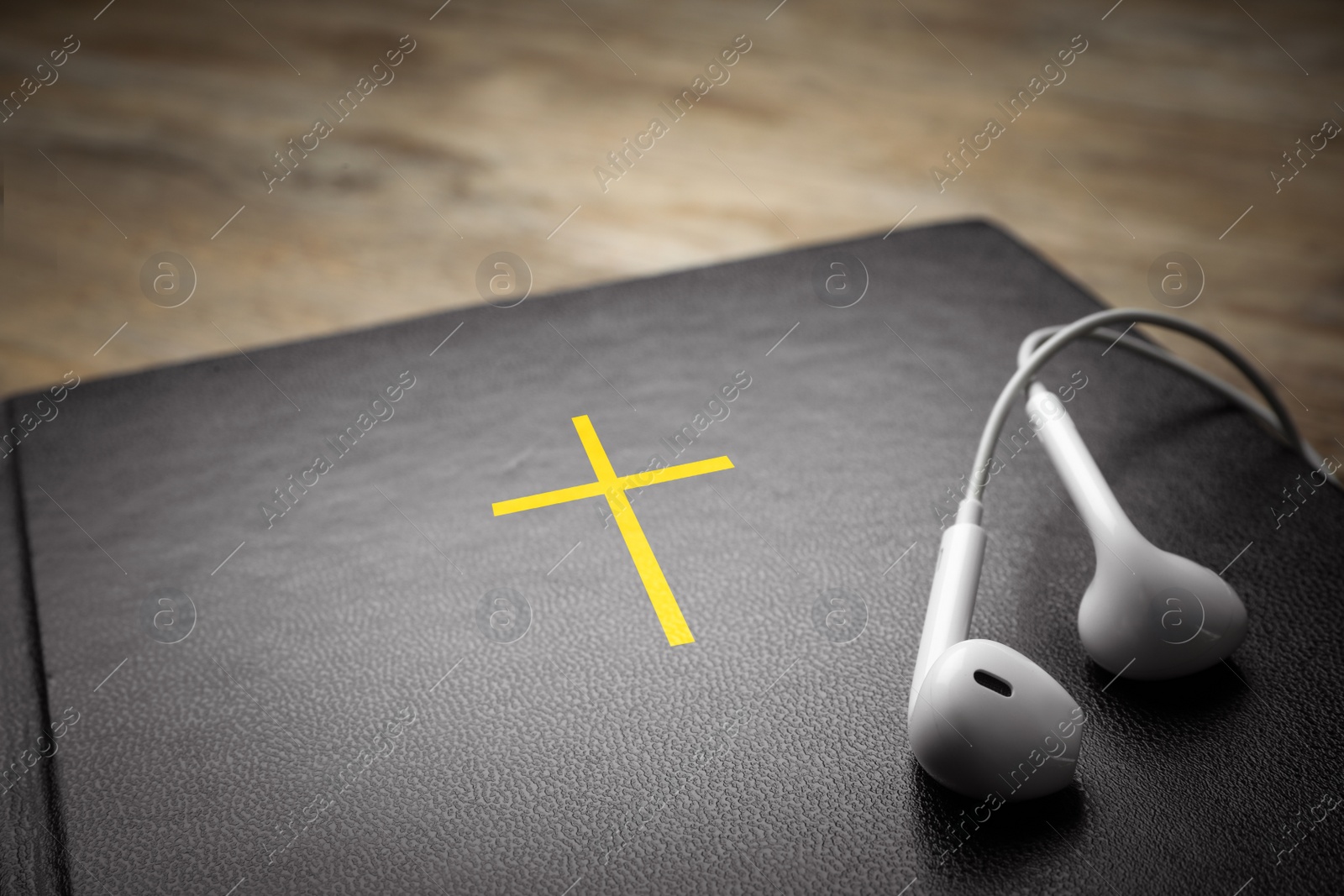 Photo of Bible and earphones on table, closeup. Religious audiobook